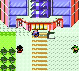 "Pokémon Crystal Version" screenshot of the player character standing outside of the entrance to Battle Tower. Two NPCs are to the left and right.